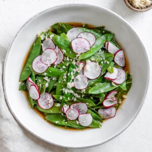 completed Spicy Sugar Snap Peas with Horseradish in a white bowl against a white surface