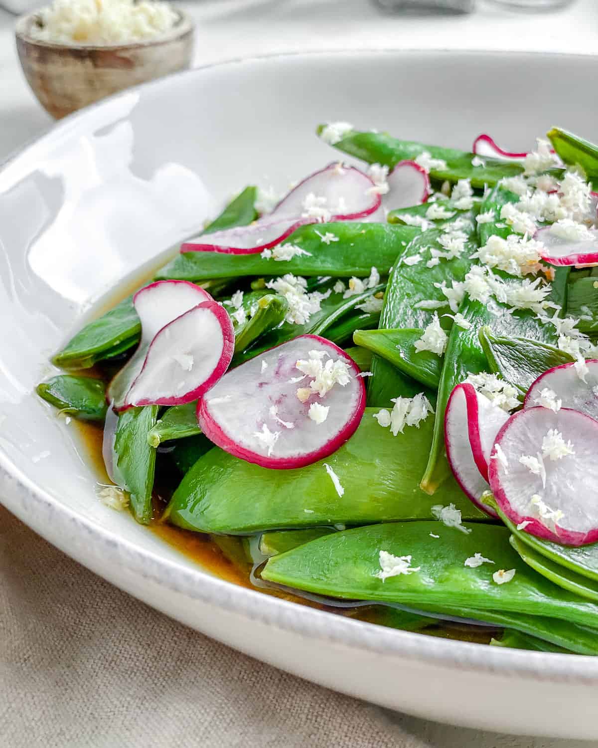 completed Spicy Sugar Snap Peas with Horseradish in a white bowl against a white surface