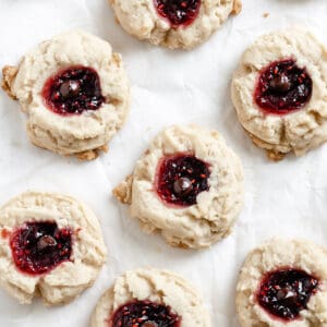 completed Raspberry Jam Thumbprint Cookies scattered on a white surface