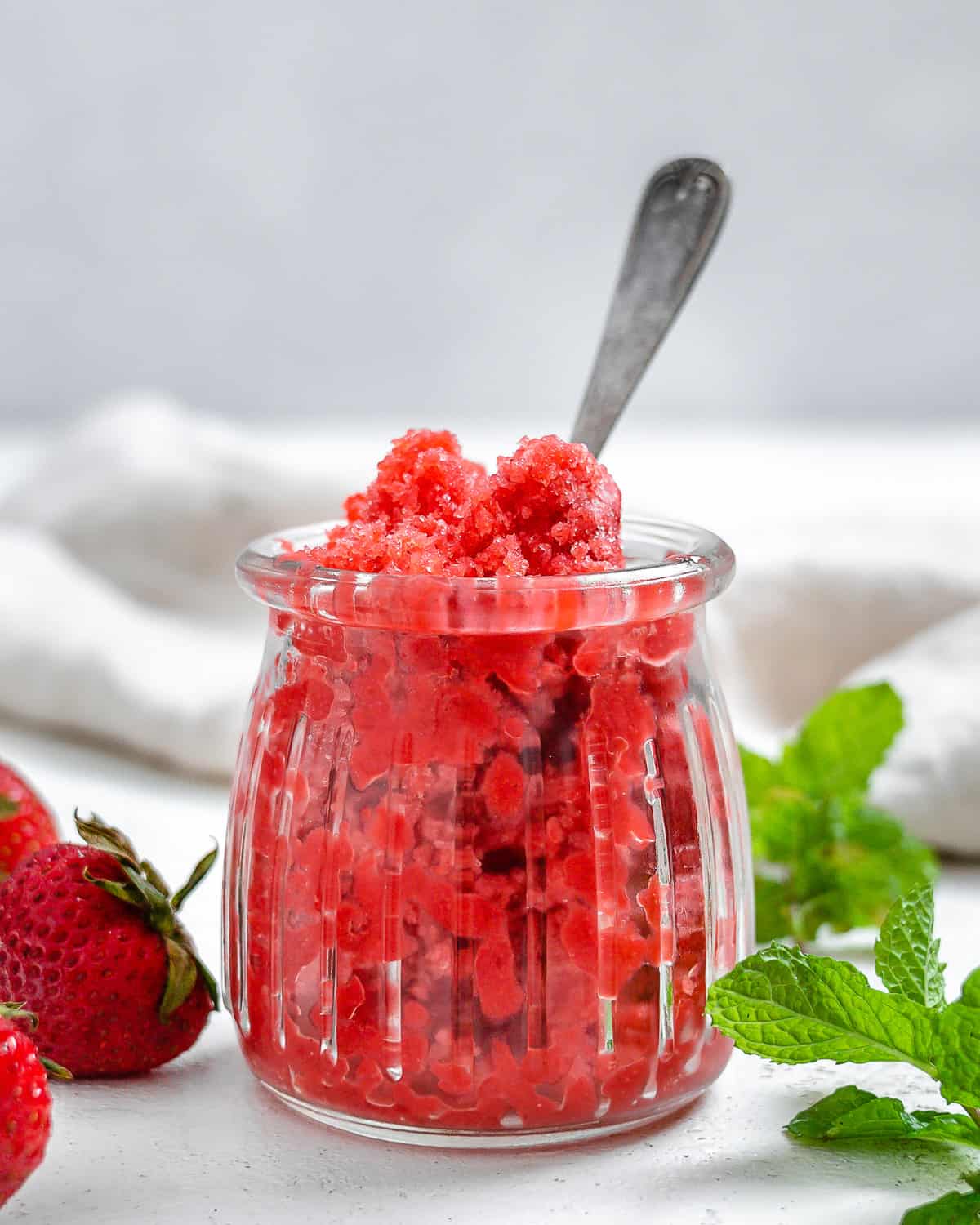 completed Strawberry Sorbet With Mint in a glass jar with ingredients in the background