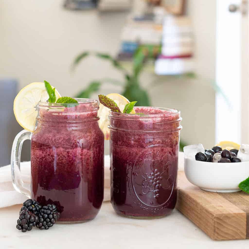 completed Mixed Berry Smoothie Recipe with Mint in two glass jars against a light surface