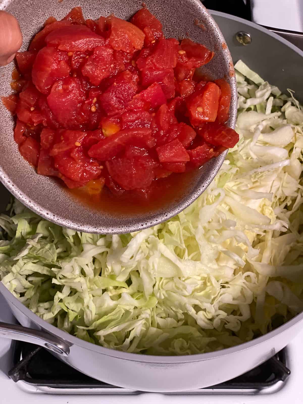 process shot of adding tomatoes to pan