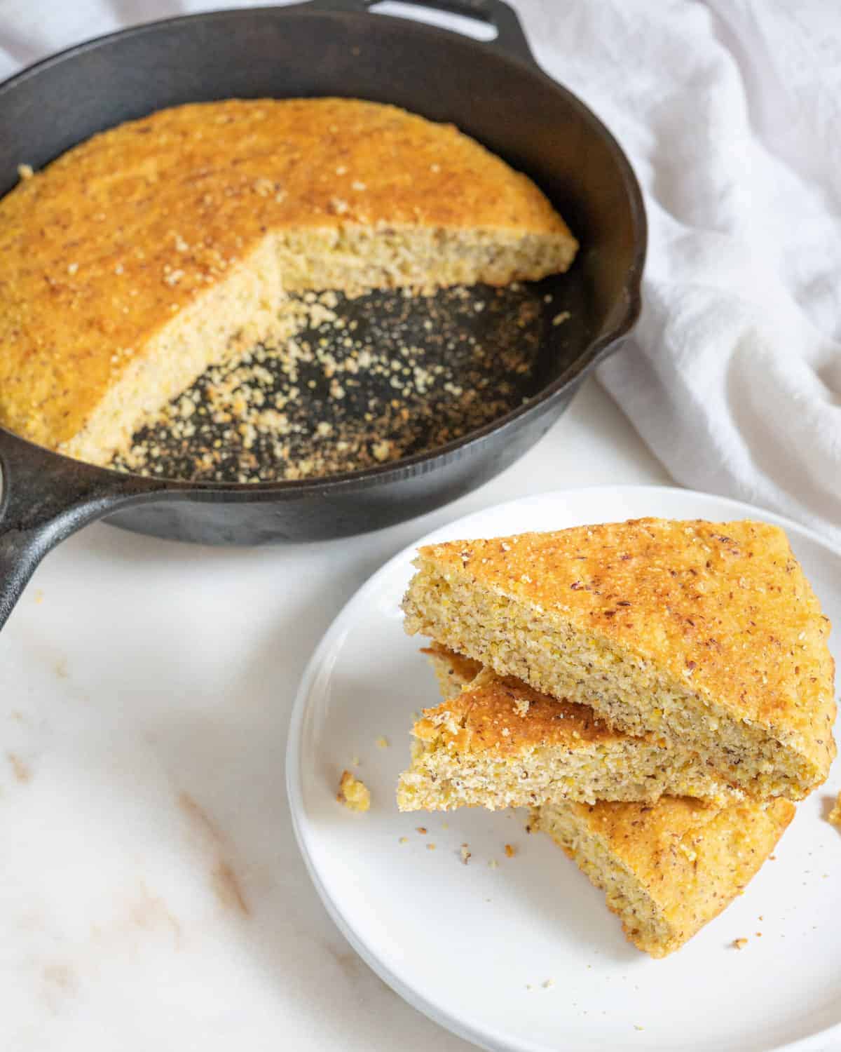 completed skillet cornbread in skillet and also plated on a small white plate