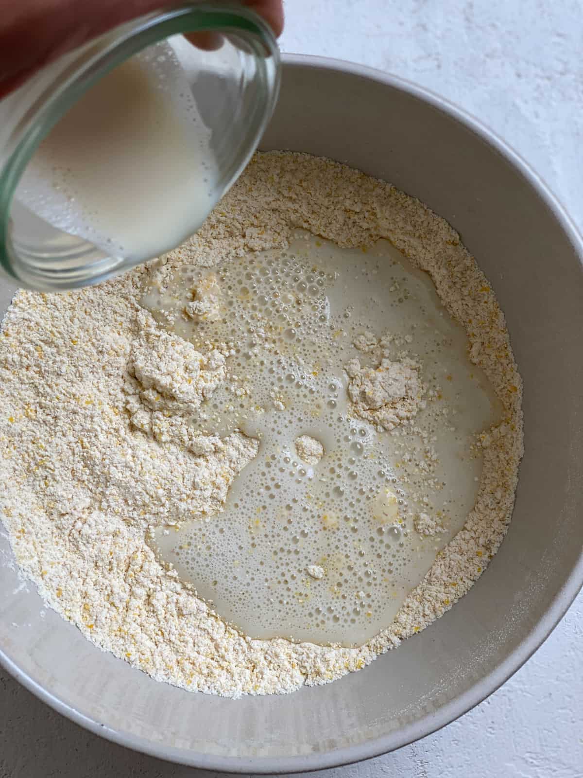 process shot of adding milk to bowl of dry ingredients