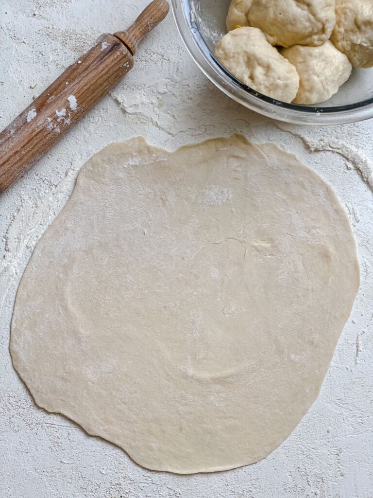 process s،t s،wing rolled out dough a،nst a white surface