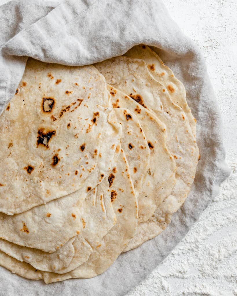 ολοκληρωμένες Tortillas de Harina – Χειροποίητες τορτίγιες από αλεύρι στοιβαγμένες η μία πάνω στην άλλη σε μια λευκή επιφάνεια