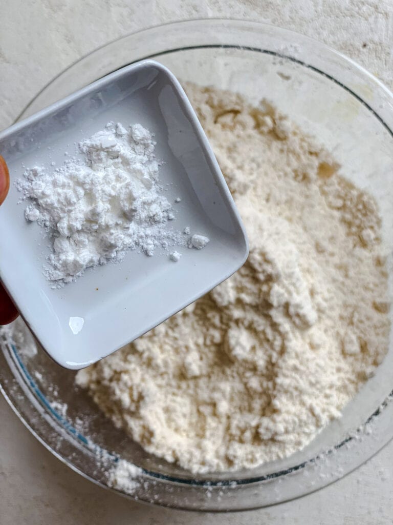 process shot of adding baking powder to mixing bowl