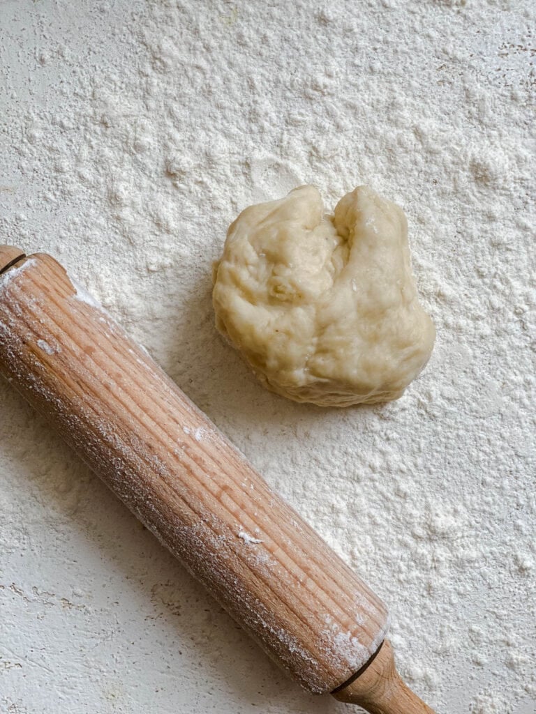 process shot showing piece of dough alongside rolling pin