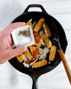 process of adding spices to pot with tempeh