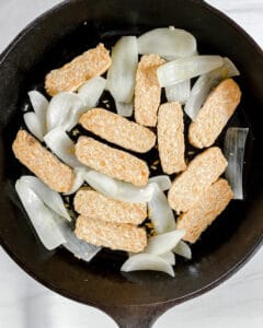 process showing sliced tempeh and onions. in a pan
