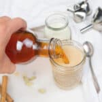 process of pouring Homemade Chai Concentrate into a mason jar with several items in a white background
