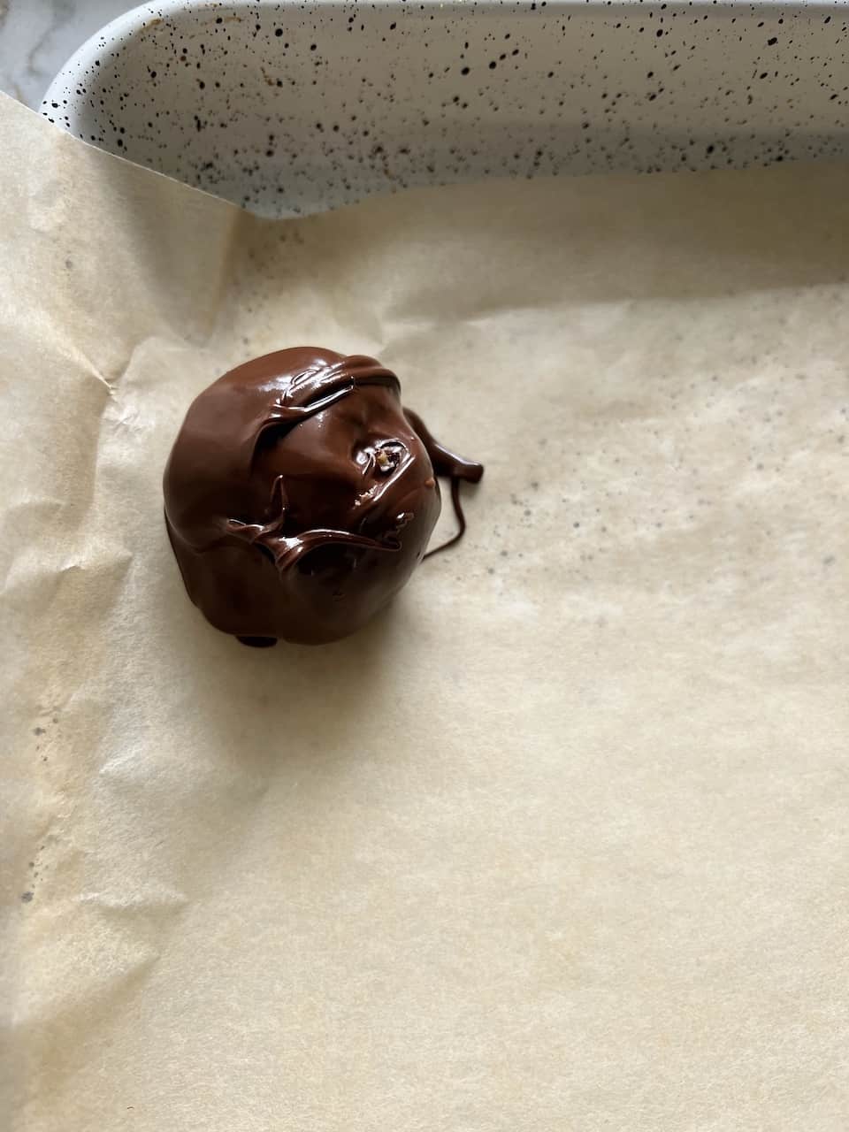 process of placing a chocolate covered bon bon on parchment paper