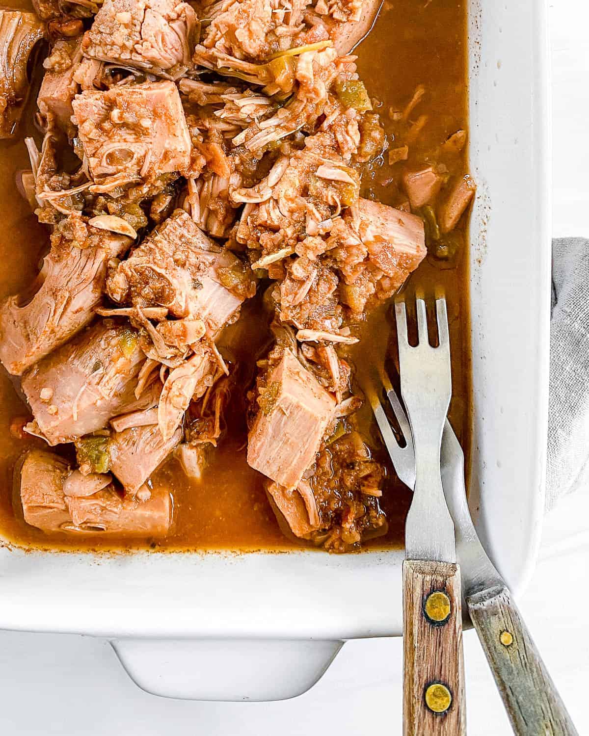 completed jackfruit carnitas in a white dish with two forks in the tray