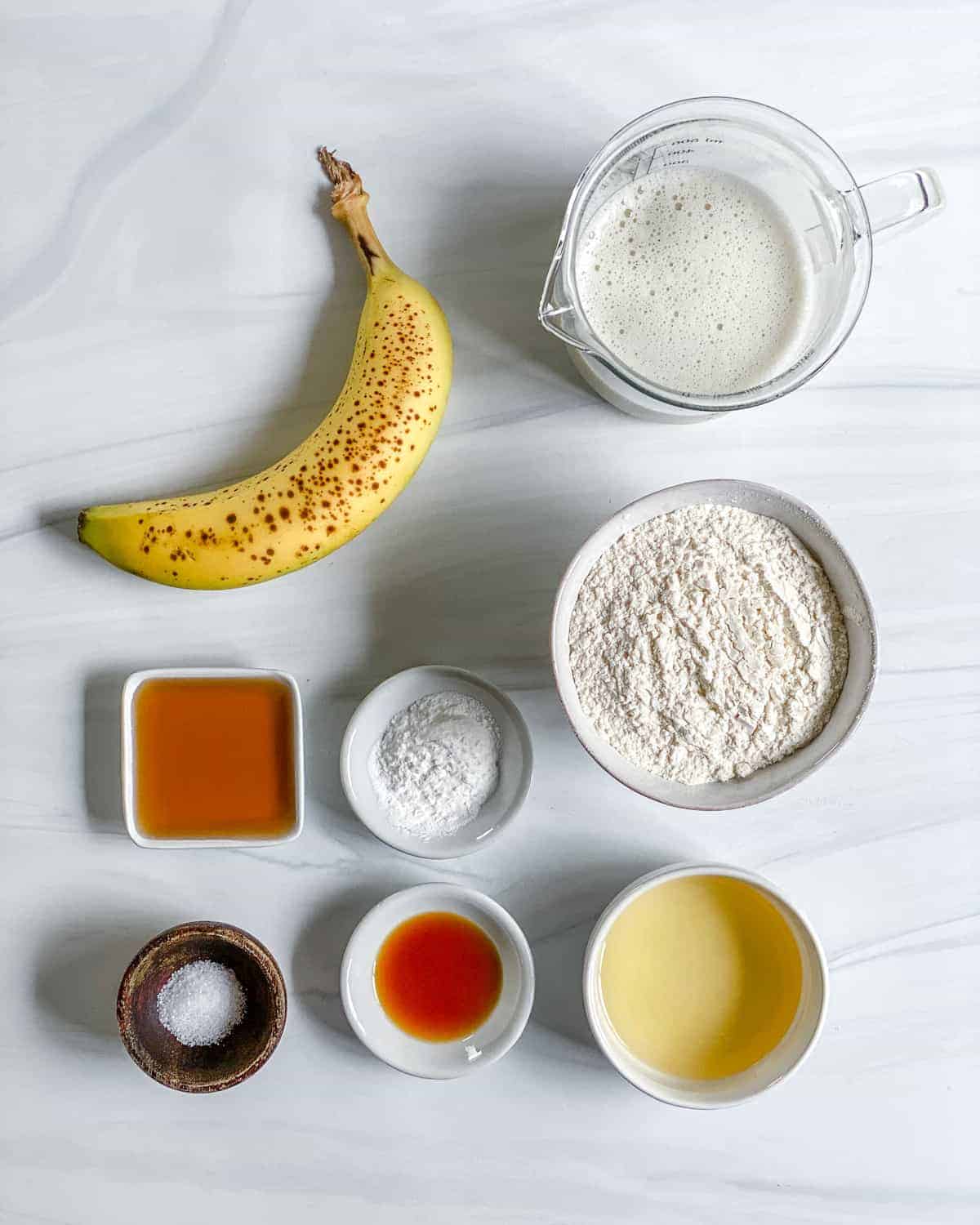 ingredients of banana pancakes spread out against a white surface