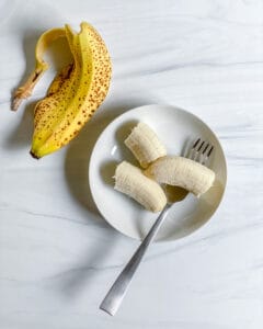 bowl of cut bananas on a small white plate against a white surface