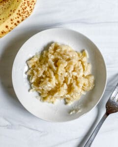 mashed banana on a white plate against a white surface
