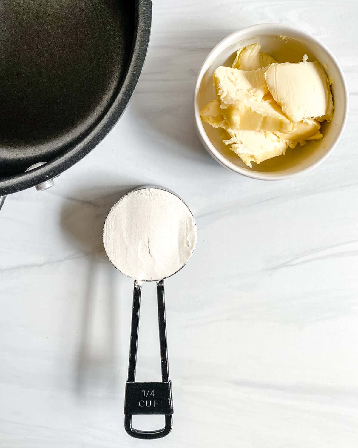 Ingredients for pumpkin sage sauce next to a black saucepan.