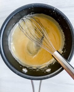 proces showing the mixing of ingredients in a black pan with a whisk