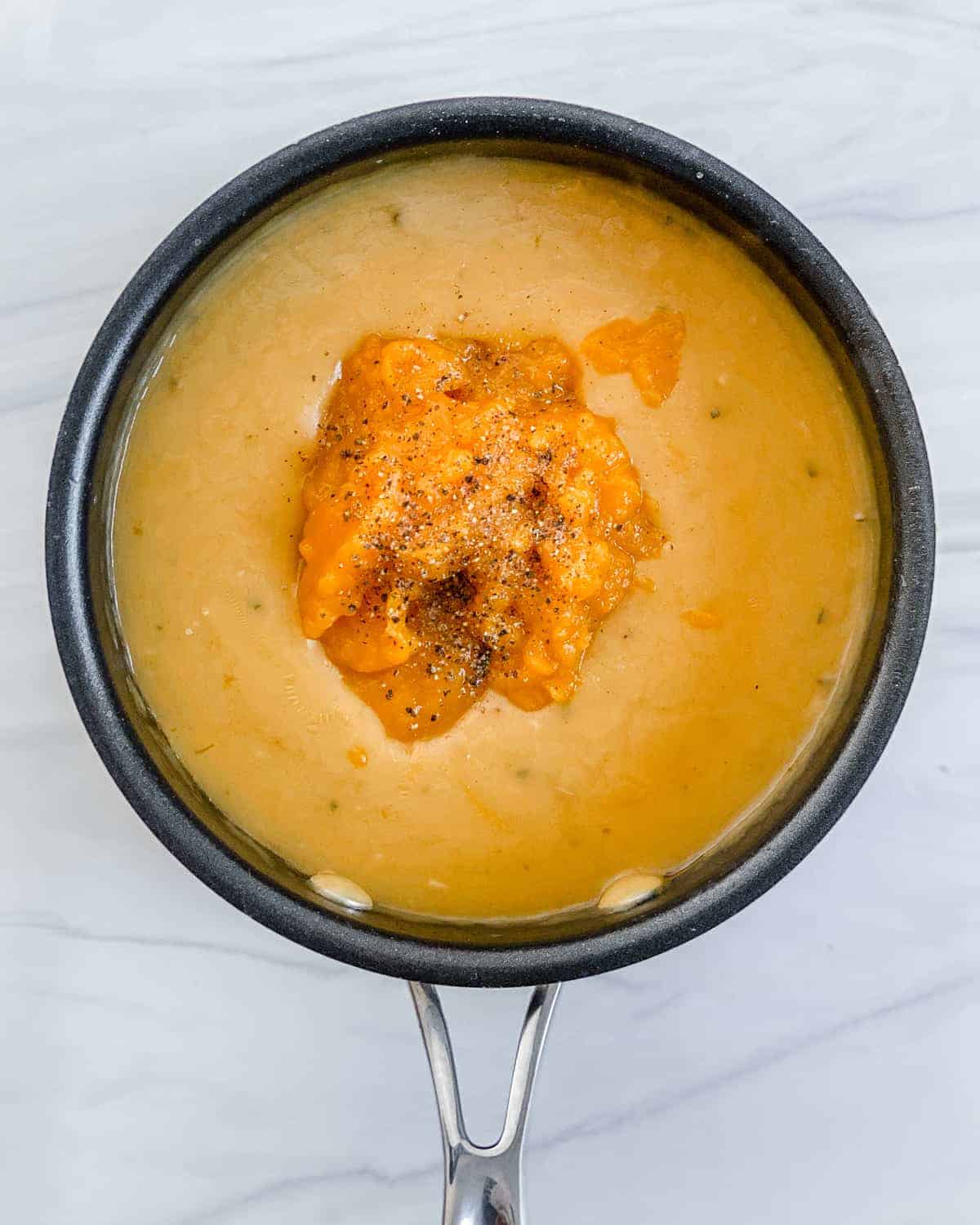 Creamy pumpkin sage sauce in a black saucepan.
