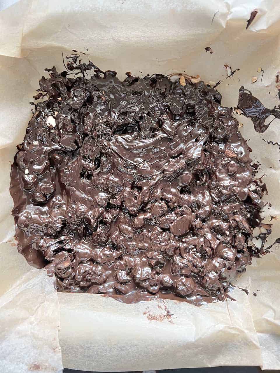 process post the mixing of vegan chocolate, dried nuts, and nuts on parchment paper laid tray
