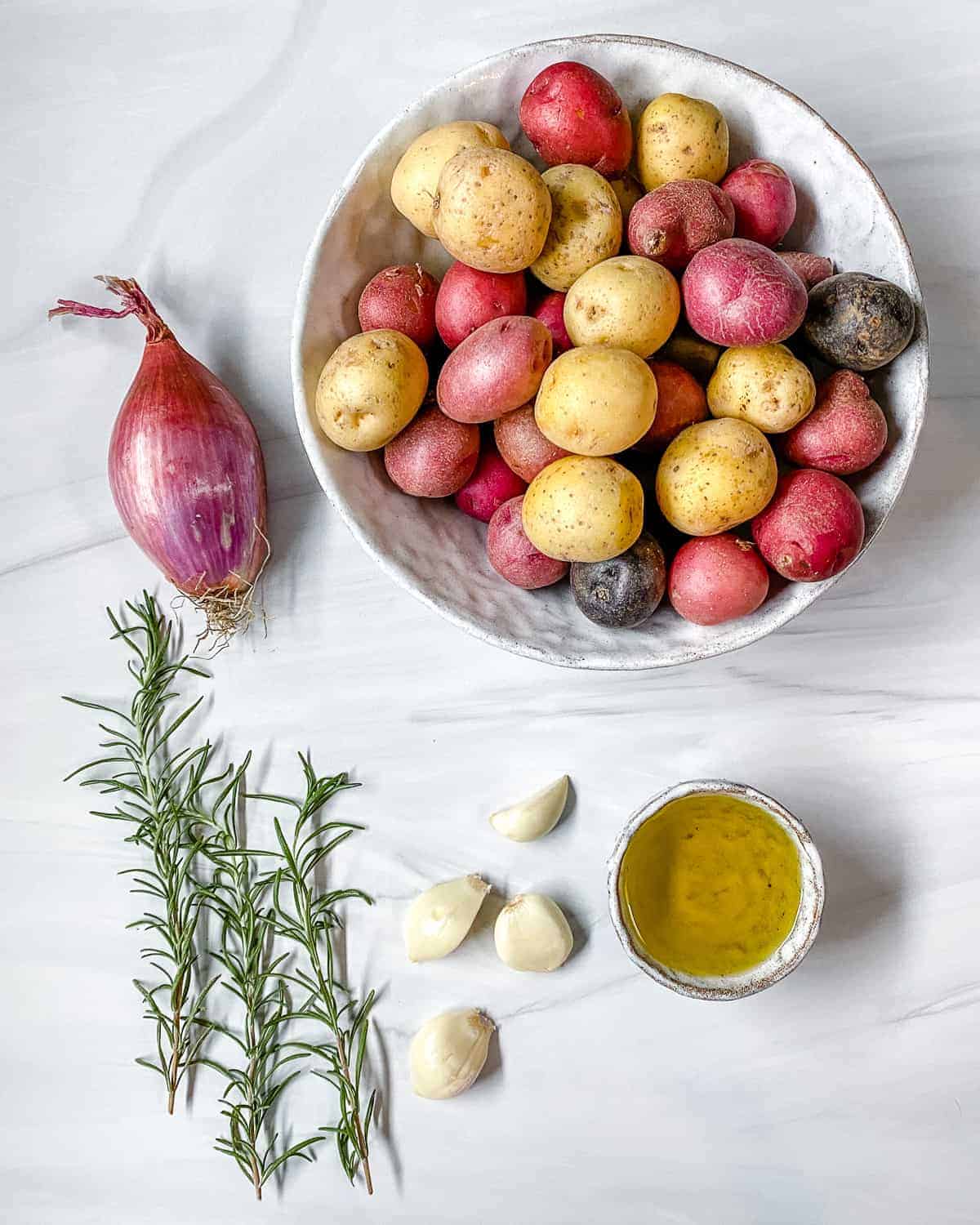 ingredients for Roasted Rosemary Potatoes measured out against a white surface