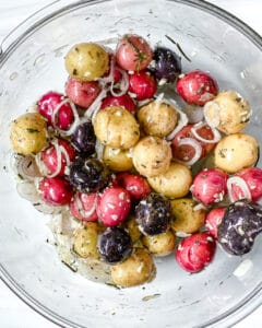 process of mixing Roasted Rosemary Potatoes ingredients in a bowl