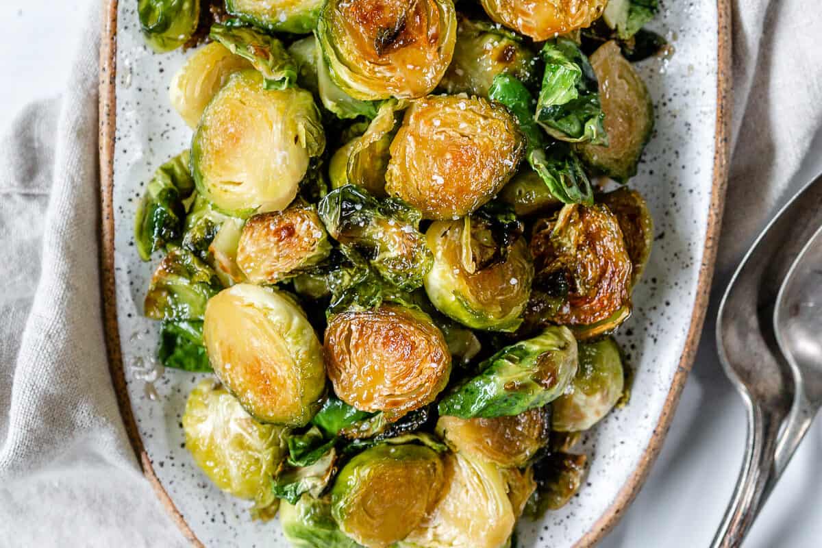 completed Sweet and Salty Brussels Sprouts in a white dish against a white background