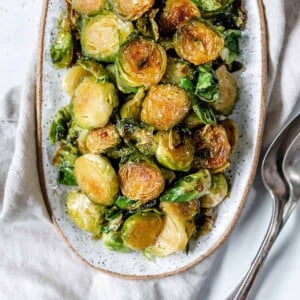 completed Sweet and Salty Brussels Sprouts in a white dish against a white background