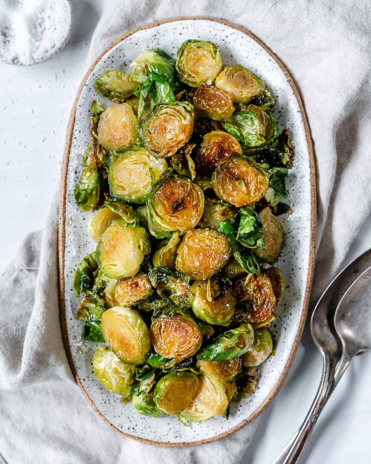completed Sweet and Salty Brussels Sprouts in a white dish against a white background
