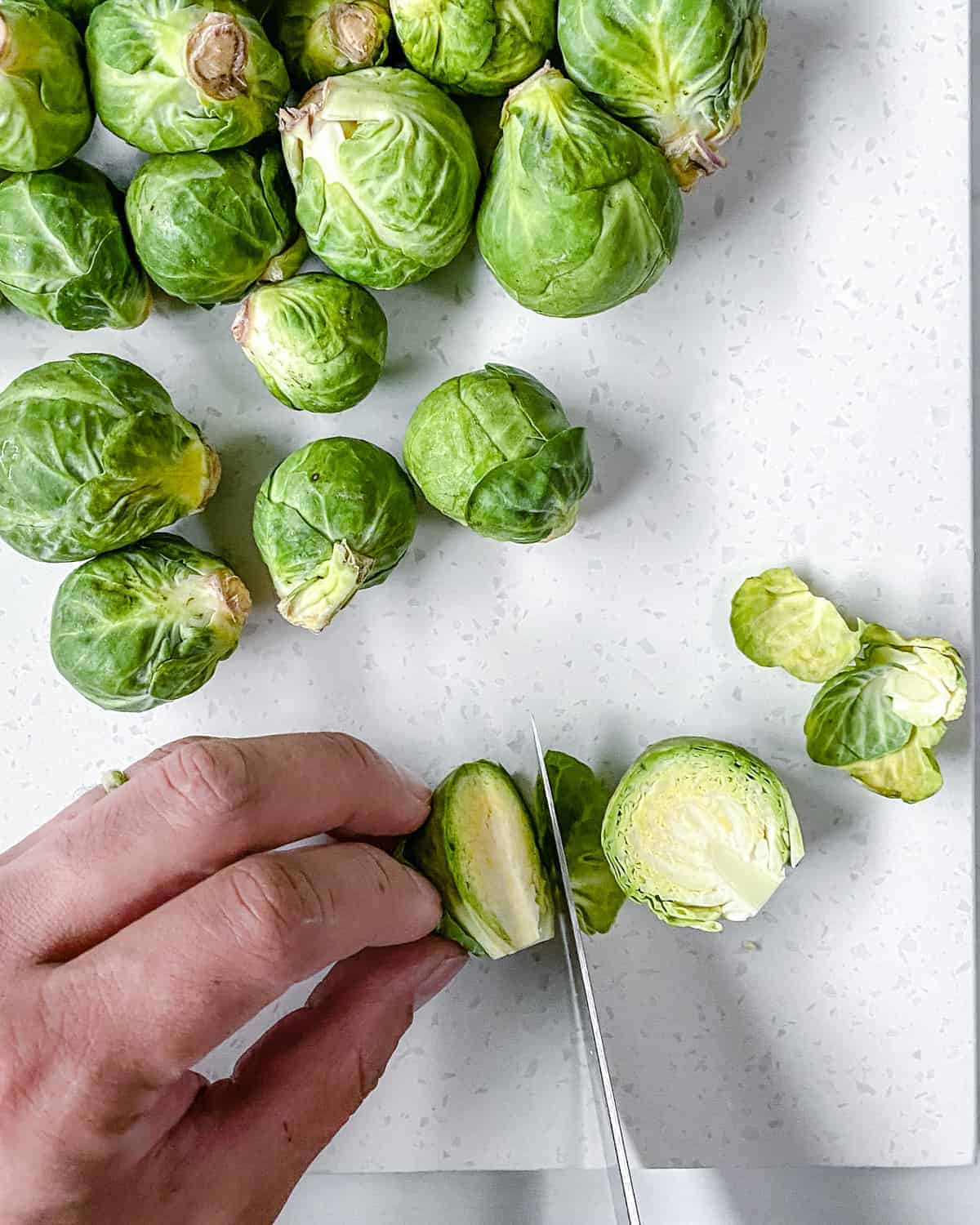 process of cutting brussels sprouts against white background