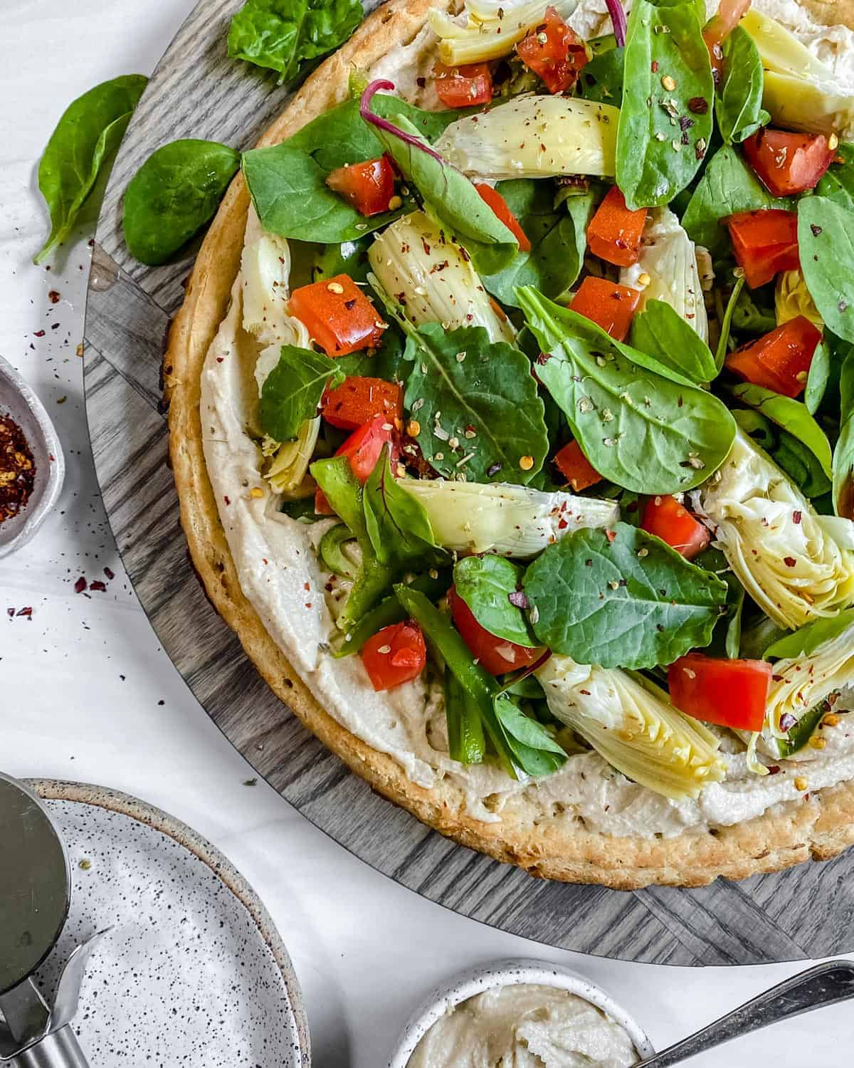 completed hummus pizza sliced on a gray surface 