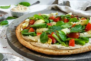 completed hummus pizza sliced on a gray surface