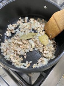 process of garlic, onions, and mushrooms cooking in a pan