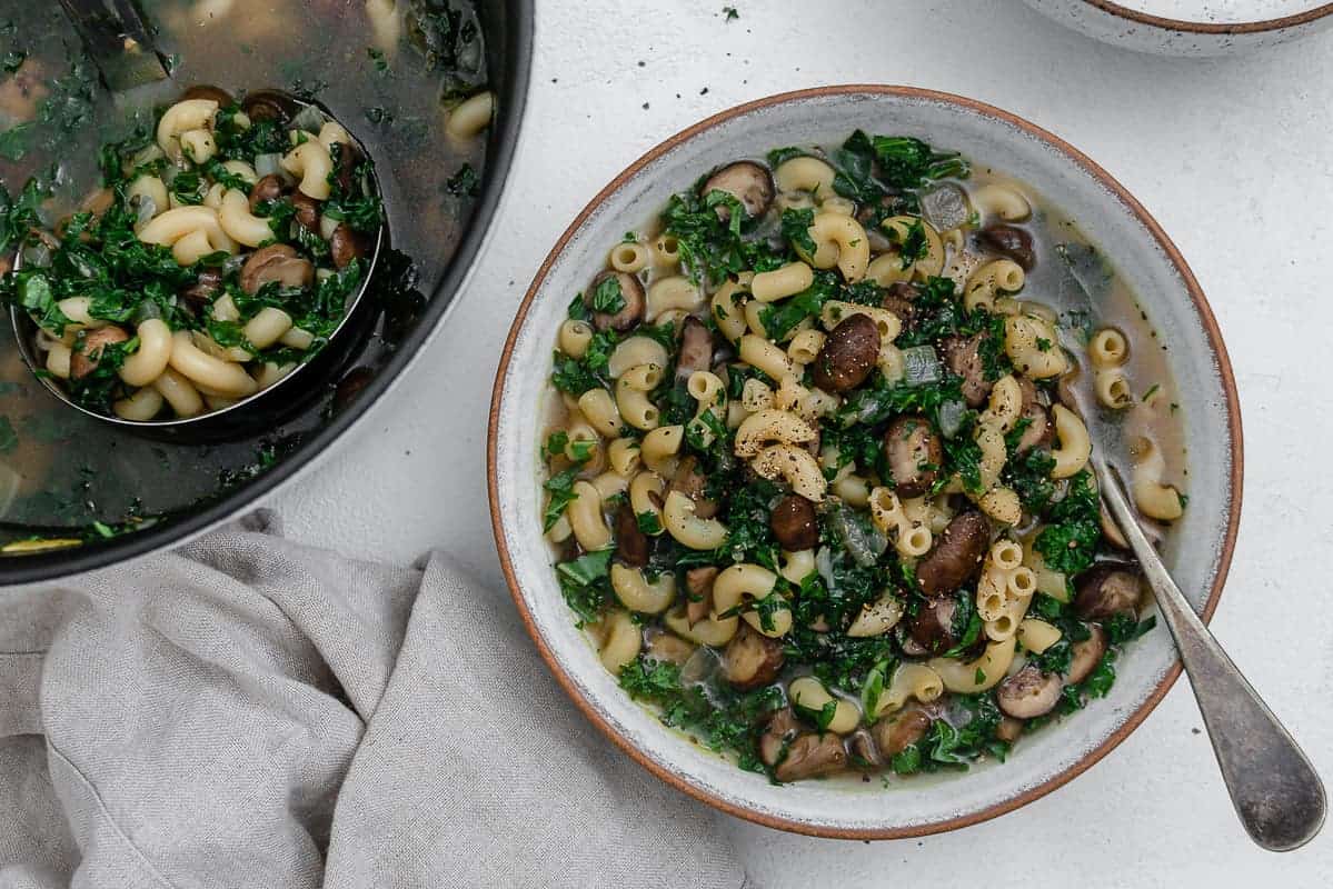 completed mushroom orzo soup in a white bowl against a white background