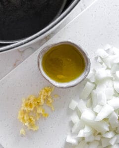 chopped garlic, onion, and olive oil in a small bowl on a white surface