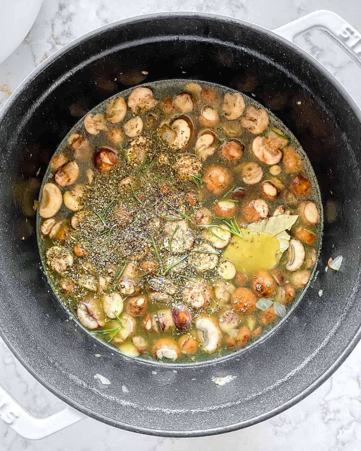 ingredients for mushroom orzo soup in a black pan