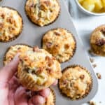 several Pineapple Walnut Muffins in a muffin pan with ingredients in the background and a close up of one muffin