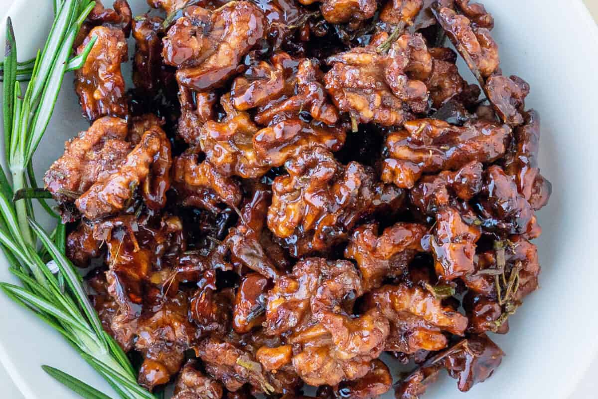 completed sweet rosemary walnuts plated on a white plate against a white surface