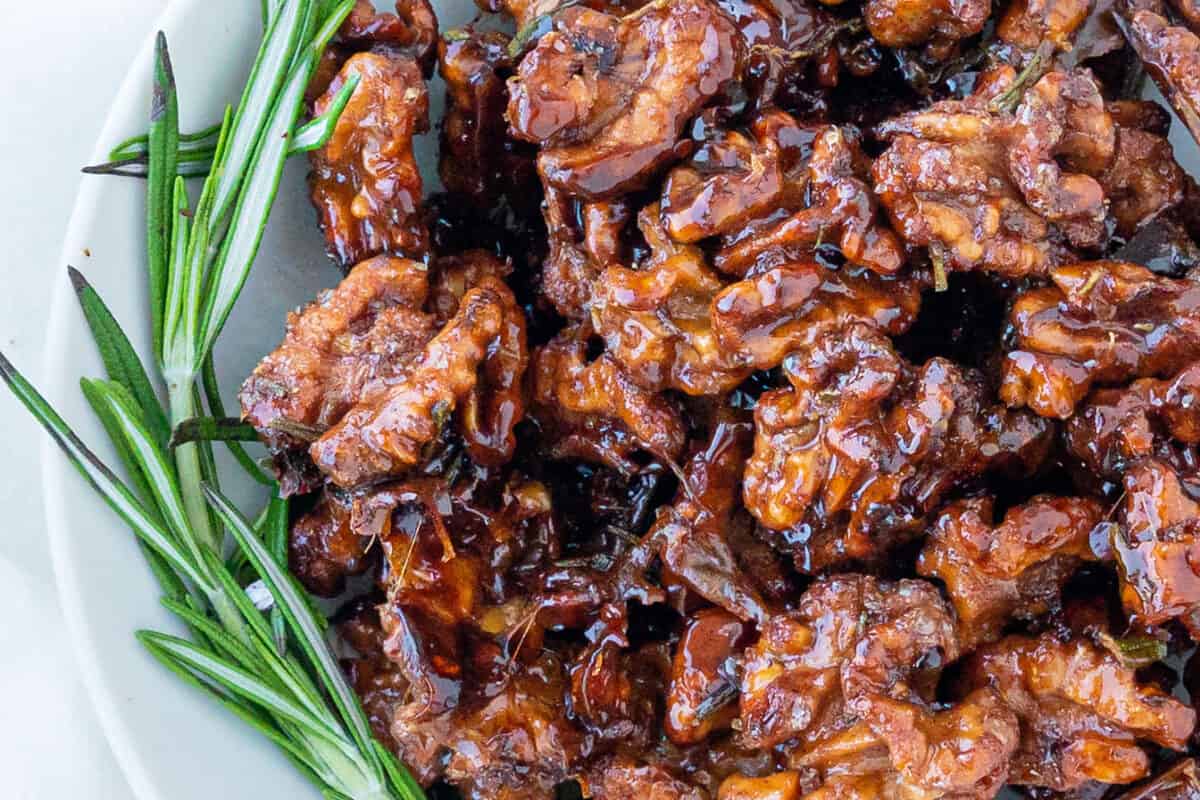 completed sweet rosemary walnuts plated on a white plate against a white surface