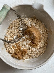 process of mixing brown sugar into bowl of oats