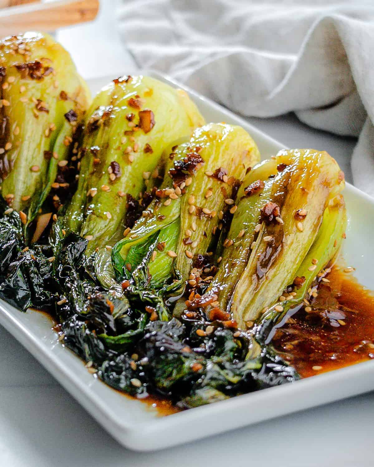 completed baby bok choy with soy sauce and garlic on a white serving tray against a white background