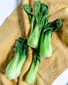 process of baby bok choy drying off against a tan cloth