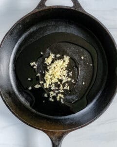 process showing garlic and oil in a black skillet