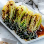 completed baby bok choy with soy sauce and garlic on a white serving tray against a white background