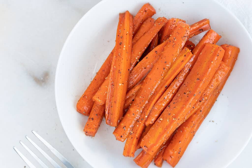 Finished cut and sliced glazed Carrots on a white plate in a white background