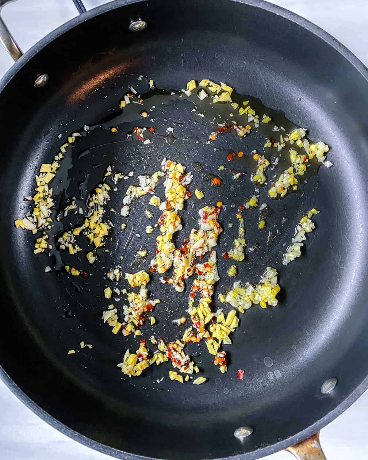 process of adding garlic to a black pan