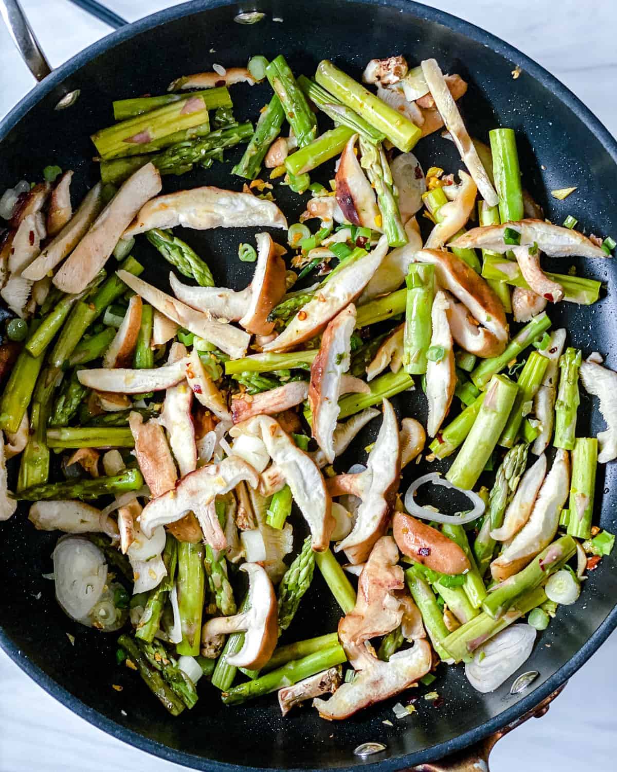 process of cooking Shiitake Asparagus Tofu Stir-fry in a black pan