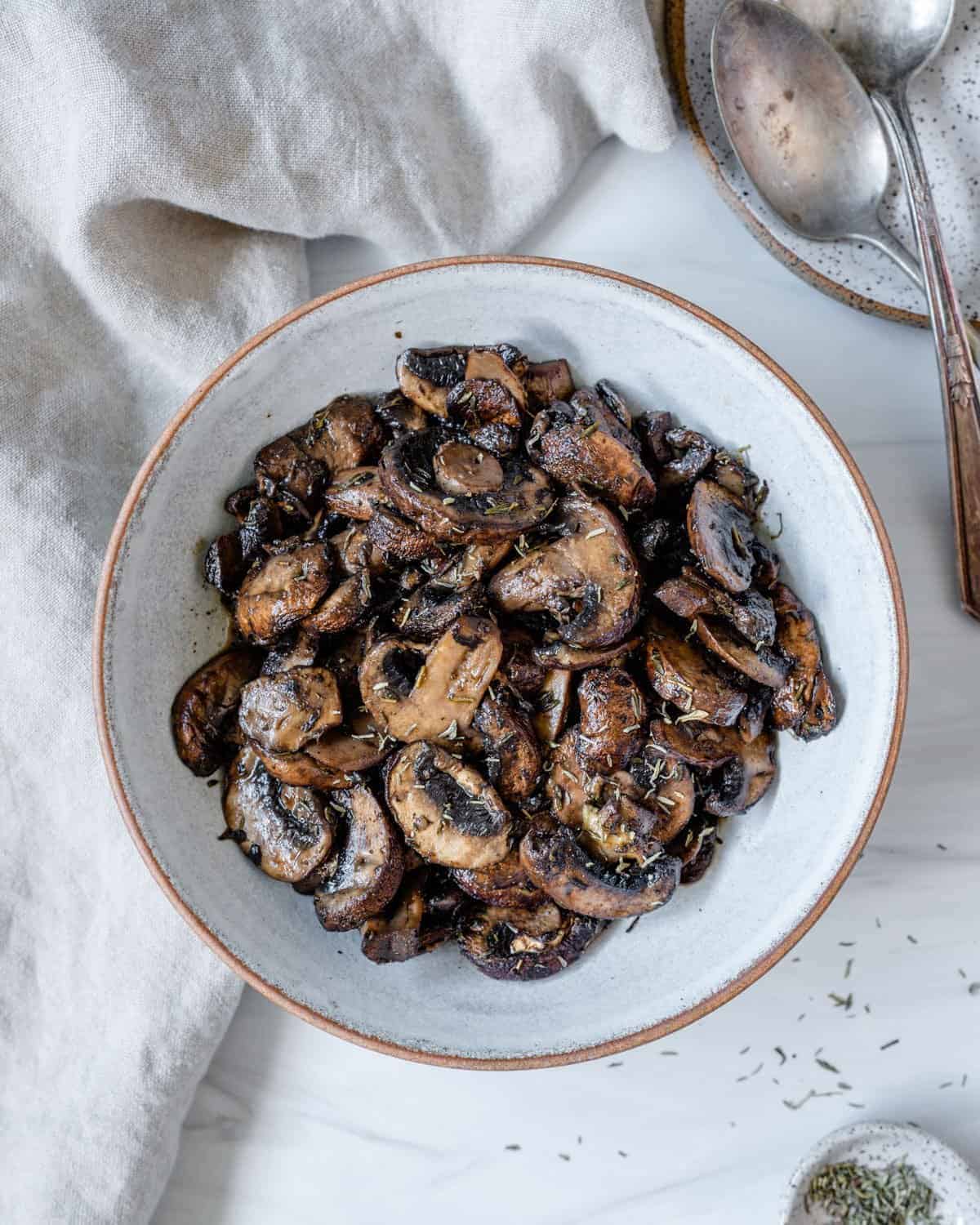 completed simple roasted mushrooms on a white plate against a white background