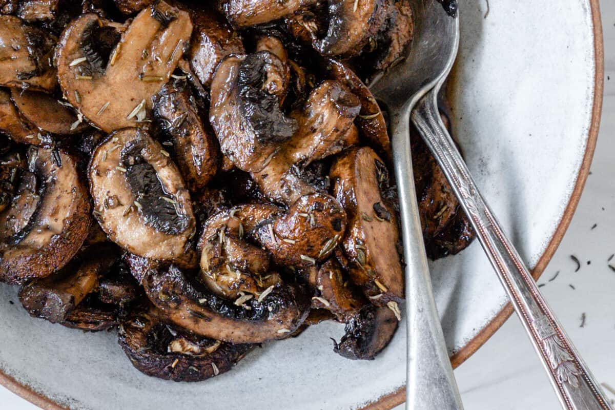 completed simple roasted mushrooms on a white plate against a white background