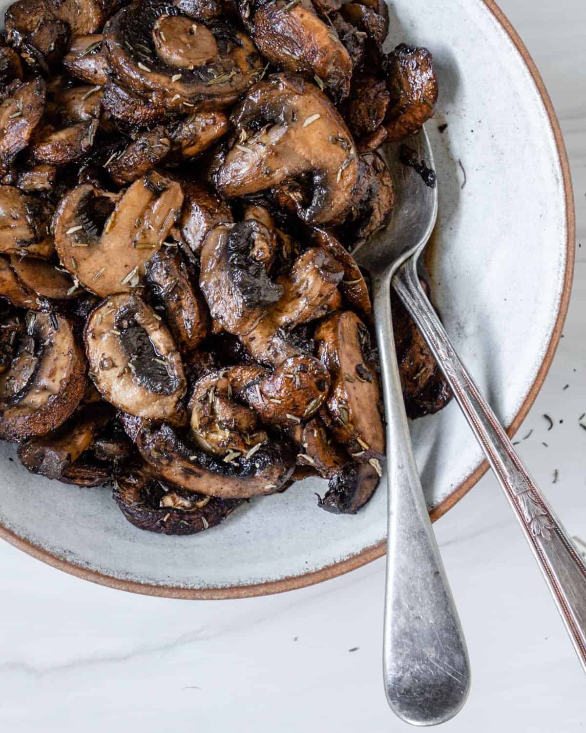 completed simple roasted mushrooms on a white plate against a white background